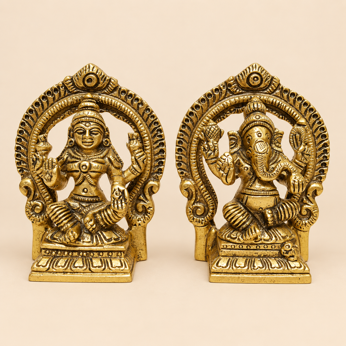 Two ornate brass Lord Ganesha and Lakshmi figurines displayed side-by-side on a plain beige background.