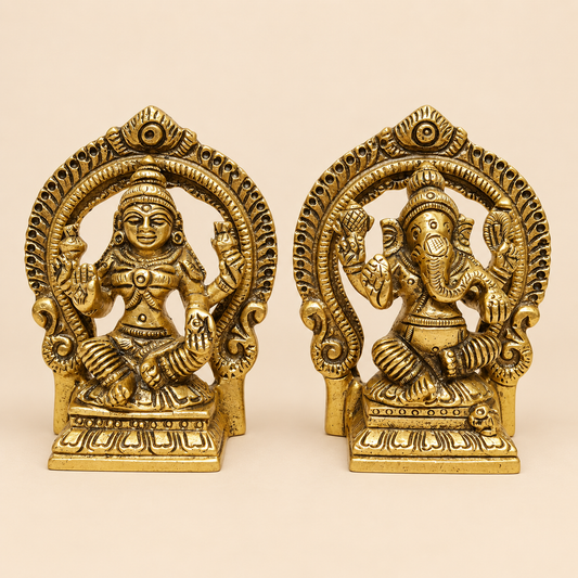 Two ornate brass Lord Ganesha and Lakshmi figurines displayed side-by-side on a plain beige background.