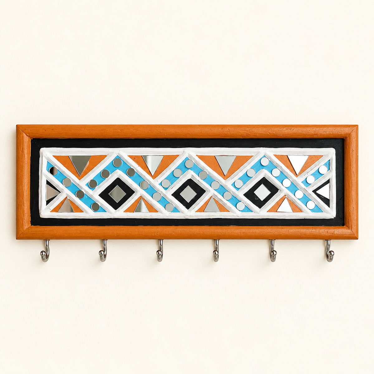 A rectangular wall mounted Lippan art keyholder with a warm orange MDF frame and five hanging hooks. The center features a colorful geometric pattern with orange, light blue, black, white, and gray shapes on a black background.