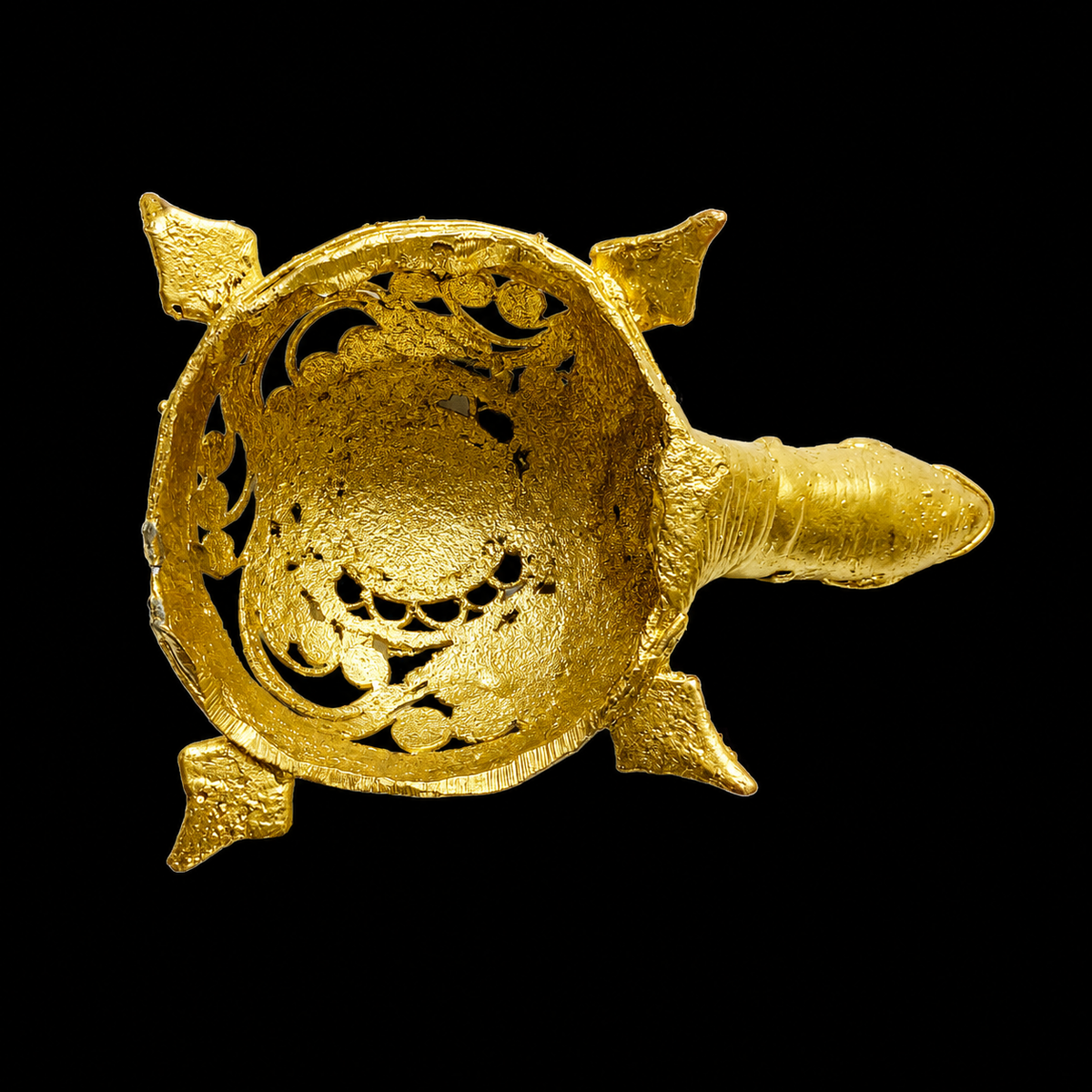An ornate gold-toned Dokra tortoise figurine with intricate filigree and spiral detailing, photographed against a solid black background.