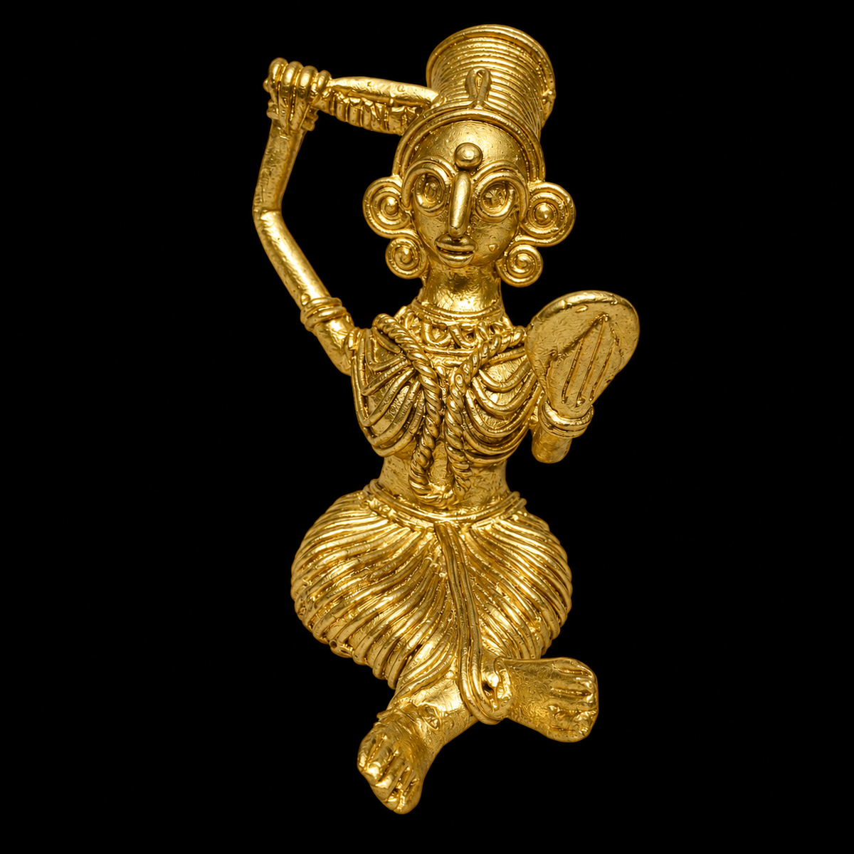 A small Dokra figurine of a stylized sitting female figure with a mirror in one hand and comb in the other, shown against a solid black background.