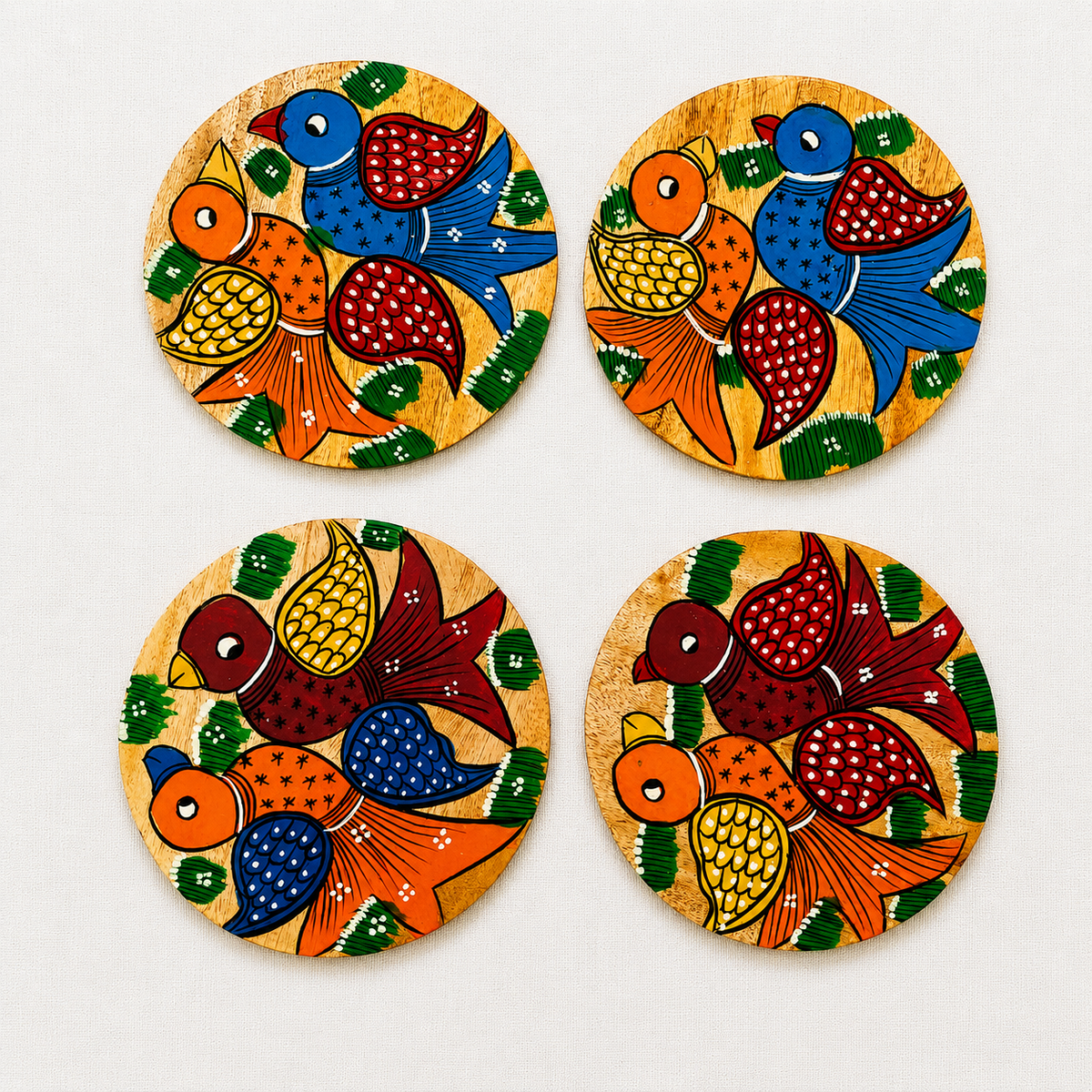 Four round wooden coasters featuring traditional Indian Patachitra art illustrations of colorful birds, arranged in a 2x2 grid on a light off-white background.