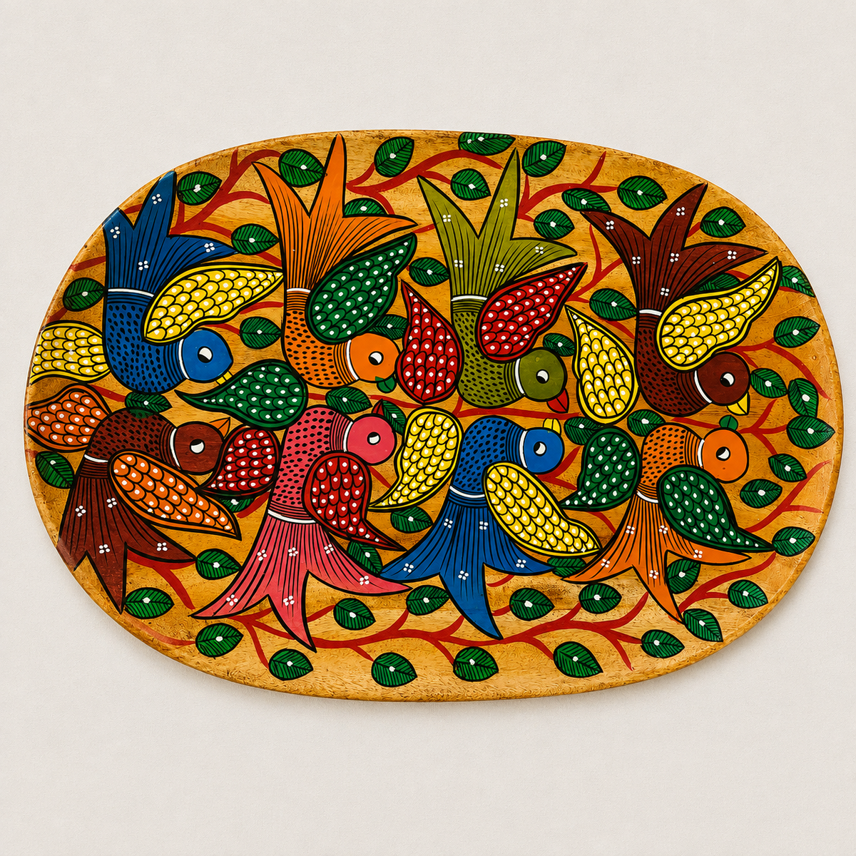 An oval hand-painted wooden serving tray with Patachitra folk art plaque featuring colorful birds and leaves on a warm yellow-orange background, photographed against a light neutral backdrop.