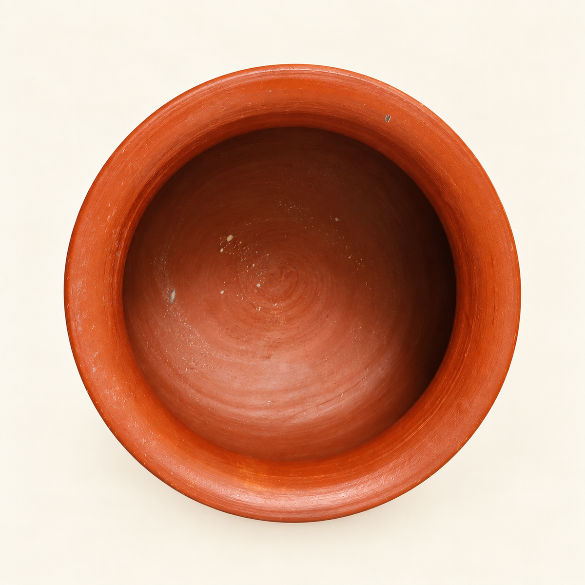 A top-down view of a terracotta clay cooking pot with a wide circular rim, shown on a plain off-white background.