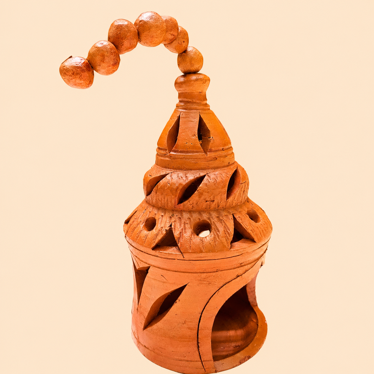 An orange-brown terracotta hanging lamp with carved cutouts and a beaded hanging loop, shown against a solid pale peach background.